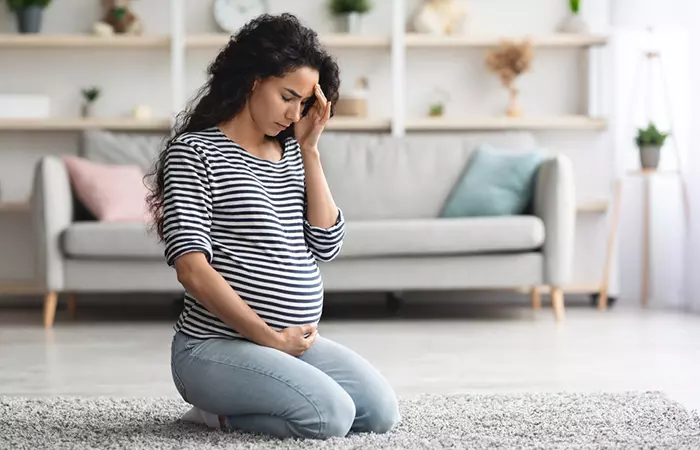 Беременная женщина испытывает мигрень из-за побочных эффектов продуктов, используемых при химической завивке.