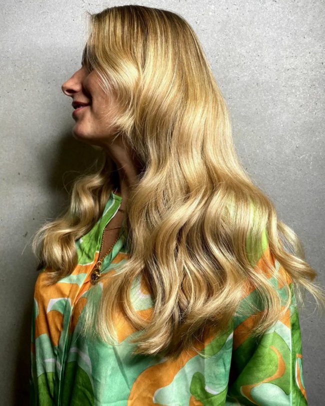 Красивый пример золотистого блонда на длинных волосах с блестящими волнами.